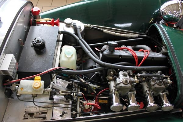 Kind Ignition Pistonheads System Xflow - The image shows the engine of a vintage car, with its metal and mechanical components fitted inside. Various colors are present, including green, black, and gray, indicating the different materials and parts involved. Electrical wires are visible, connecting the engine components and adding complexity to the scene. There are jugs labeled "diesel oil," suggesting the type of oil used in the engine. The engine appears well-maintained and is likely for a small or classic car.