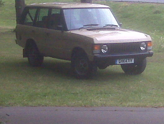 Rover Restore Range Classic Pistonheads - In the heart of a serene green field, a vintage SUV stands alone, its beige color contrasting beautifully with the natural surroundings. It's parked facing towards the right, ready to venture onto the road or stay put, basking in the sunlight. The number plate reads "G447Y", a detail that adds a personal touch to the vehicle. The image exudes a sense of tranquility, of a solitary journey or perhaps a moment of respite before hitting the road again.