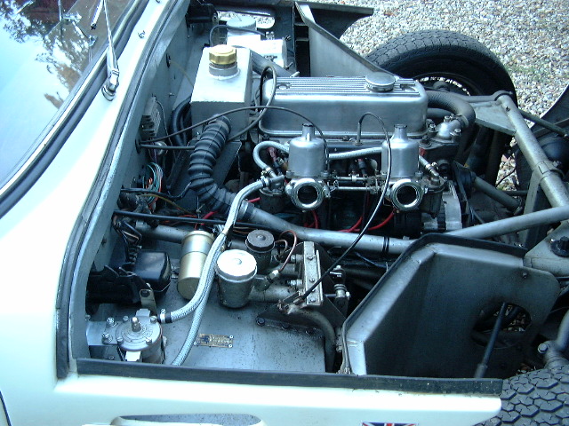 Clear picture of Grantura MK1 dashboard. - Page 1 - Classics - PistonHeads - The image presents a complex collection of mechanical parts. The engine, which appears to be the central focus of the image, is exposed and includes various components such as hoses, filters, and possibly other engine parts. The car is positioned against a backdrop that seems to be a gravel surface, suggesting an outdoor or perhaps informal location. The overall scene conveys an air of curiosity and technical interest, perhaps indicating a passionate owner or hobbyist.