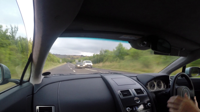 ARE THESE POOR LANE MARKINGS? - Page 1 - Advanced Driving - PistonHeads - The image showcases the interior of a car on a journey, with an expansive view through the windshield of a two-lane highway. A single car ahead is visible, driving on the same road. The driver's side mirror and passenger side windows provide additional points of interest. The perspective is most likely that of the car's driver, looking forward into the road ahead.