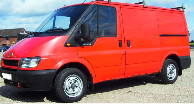 Pistonheads - The image depicts a vibrant red transit van parked on a gravel surface. The van is possibly a cargo vehicle with large windows on the side. It has a sleek and modern design, with a black stripe running down its side, enhancing its aerodynamic appearance. The vehicle features all-black tires and wheels, which contrast with the bright red body. The sky and blades of grass visible in the image suggest that the photo was taken outdoors, possibly in a rural or semi-rural setting. The van radiates a sense of readiness for work, travel, or transportation.