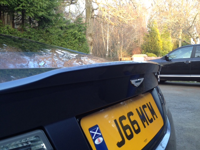 DBS wheels on DB9 - (more or less) - Page 1 - Aston Martin - PistonHeads - The image captures a moment of two cars parked side-by-side on a paved area. The back of a blue Jaguar is prominently displayed in the foreground, its metallic sheen reflecting the surrounding environment. The license plate, reading "J66 MCM", is clearly visible, suggesting its uniqueness. 

In the background, a black SUV is parked neatly beside the Jaguar. The vehicles are the primary focus of the image, standing out against the backdrop of a partially visible natural setting, with trees and foliage hinting at the presence of a forest or a park. The overall atmosphere seems peaceful and serene.