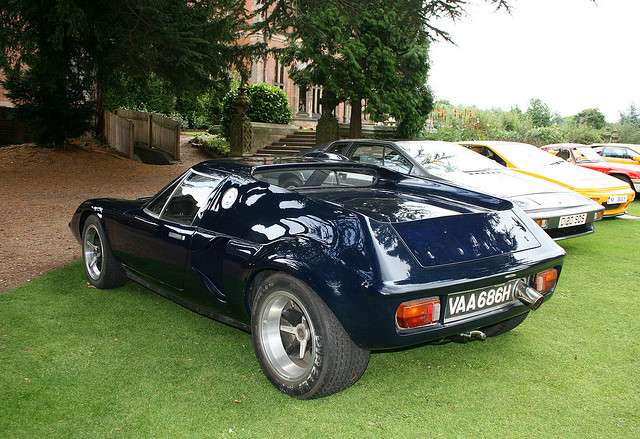 Lotus Europa 1966-1975 & tuning & conversions etc - Page 1 - General Lotus Stuff - PistonHeads - This image displays several cars parked together on a grassy area. The foreground of the image features a dark blue convertible sports car with distinctive styling typical of mid-20th century cars, prominently displaying a license plate that reads "VAA 686H." Behind it, there is a row of additional cars, including a white convertible sports car and a yellow car, suggesting a gathering or exhibit. The setting is outdoors under what appears to be an overcast sky, with tall trees in the background, indicating a private or semi-private grounds, possibly a garden or a driveway of a residence.