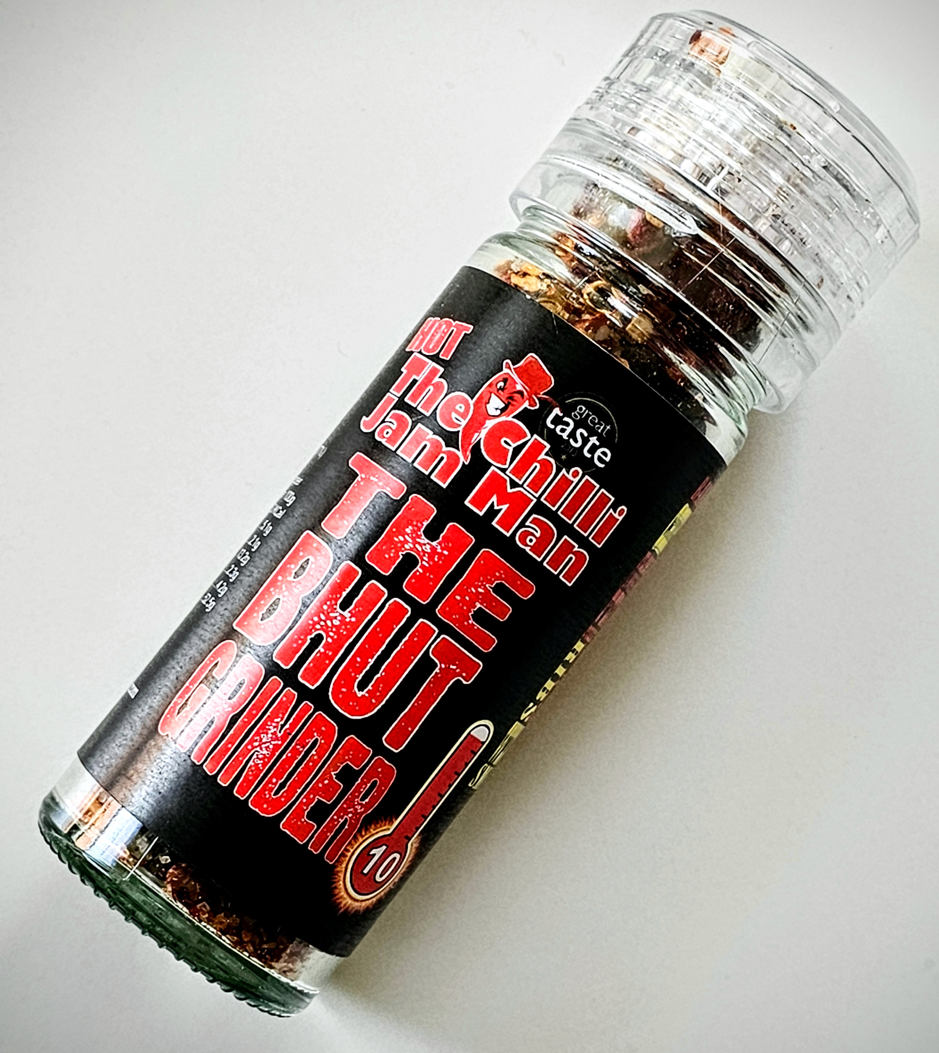 Pistonheads - The image features a jar of spices or seasonings, prominently displayed against a white background. The label on the jar is predominantly black with text that reads "The Chili Man" at the top and "The Butt Blinder" in bold red letters at the bottom. The middle part of the label seems to have additional text, possibly branding or flavor details, but it's not fully legible. The spice jar appears to be a product from the 'Chili Man' brand, as indicated by the logo on the top left corner. The overall style of the image is straightforward and commercial, likely intended for advertising purposes.