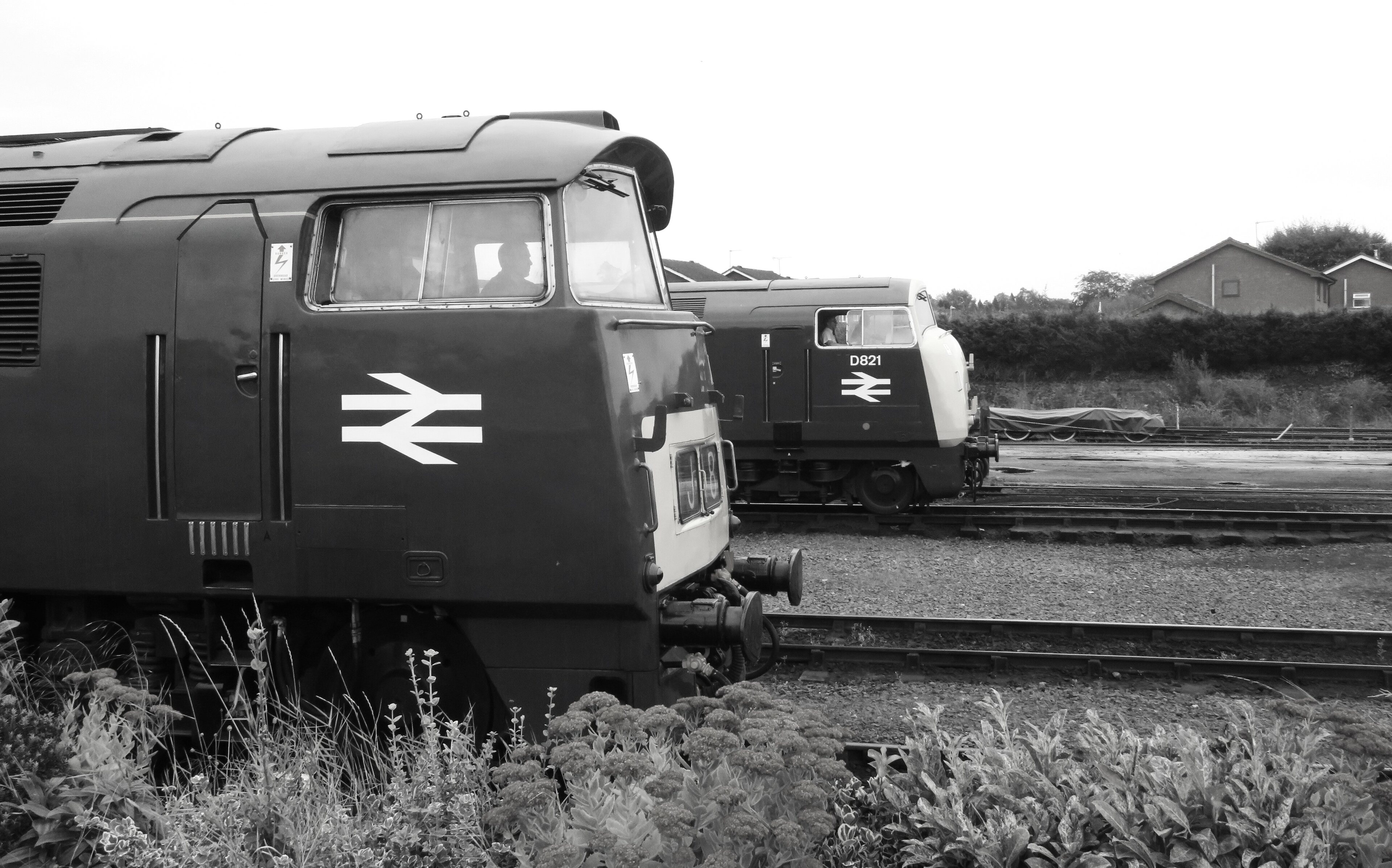 Loco sheds and other railway buildings... - Page 37 - Boats, Planes & Trains - PistonHeads UK - The image captures a tranquil scene at a train station. Two robust, dark green locomotives are parked side by side on the tracks. They are large and imposing, indicative of their strength and purpose. 

The sky above is overcast, casting a soft, diffused light over the scene. This creates an atmosphere of calmness, as if time has momentarily paused. 

In the background, there's a solitary figure of a person, perhaps waiting for their train or simply enjoying a quiet moment at the station. The person is dressed in casual attire, adding to the relaxed ambiance of the scene. 

Overall, the image paints a serene picture of life at a train station, with the powerful locomotives ready for their next journey and the single individual providing a sense of scale and human presence amidst the industrial setting.