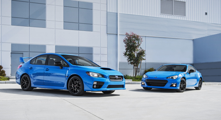 Just bought a 2016 STI  - Page 1 - Subaru - PistonHeads - The image shows a pair of blue sports cars parked side by side against the backdrop of a building and a tree. The vehicles have a sleek, aerodynamic design, and their exteriors exhibit a glossy finish. The scene appears to be set outdoors, with the lighting suggesting it may be daytime. The presence of these cars, which are often associated with high-performance driving, implies that the image might be used for advertising or editorial purposes related to automobiles.