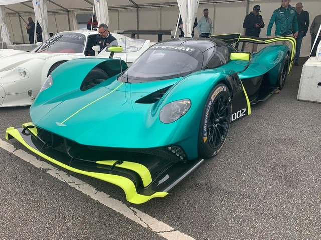 How about an Aston photo thread! - Page 217 - Aston Martin - PistonHeads UK - The image depicts a vibrant and modern sports car parked in what appears to be an indoor auto show or similar event. The car is predominantly green, with accents of yellow and teal. It's a low-roof model with a sleek design, featuring aerodynamic elements such as a front splitter and side skirts. The car's wheels are black with a unique wheel cover design that adds to its sporty appearance. There are no visible texts or logos in the image, which suggests that the focus is on the vehicle itself.