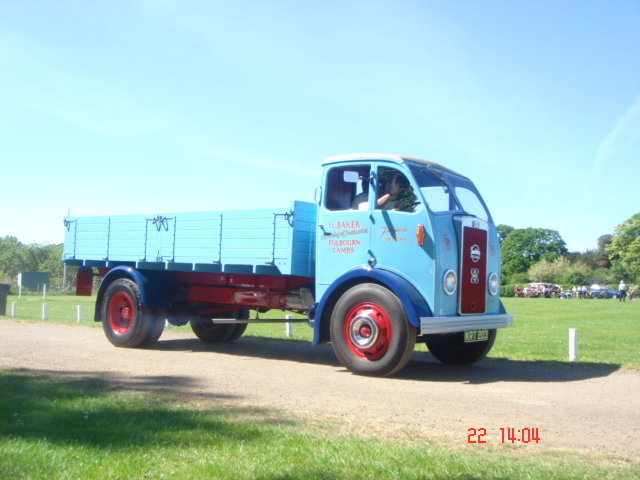 Old Warden car show - Page 1 - Classic Cars and Yesterday's Heroes - PistonHeads - The image depicts a tranquil rural scene, with a vintage, blue Ford Ranger truck parked on a dirt road. The truck, characterized by its red side panels and spare tire mounted on the rear, is the main focus of the image, occupying a substantial portion of the frame. The license plate of the truck proudly displays the text "F UEL ECON". Sitting behind the wheel is a person who appears to be overseeing the truck, suggesting a sense of management or control over the vehicle. In the background, there's a green field that stretches out into the distance, adding to the serene and undisturbed setting. The time stamp in the bottom right corner of the image reads "22 14:04", suggesting when the photo was taken.