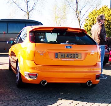 What crappy personalised plates have you seen recently? - Page 433 - General Gassing - PistonHeads - The image shows an orange Ford Focus parked in a parking lot. The car's vibrant color stands out against the more muted tones of the asphalt where it's parked. In the background, there are trees providing a green backdrop to the scene. There are also some other cars parked in the distance, but they're not as clearly visible as the main subject of the photo, the orange Ford Focus. The sky in the image suggests it may be a sunny day, but there are no direct indicators of the time of day or the specific location where this photo was taken.