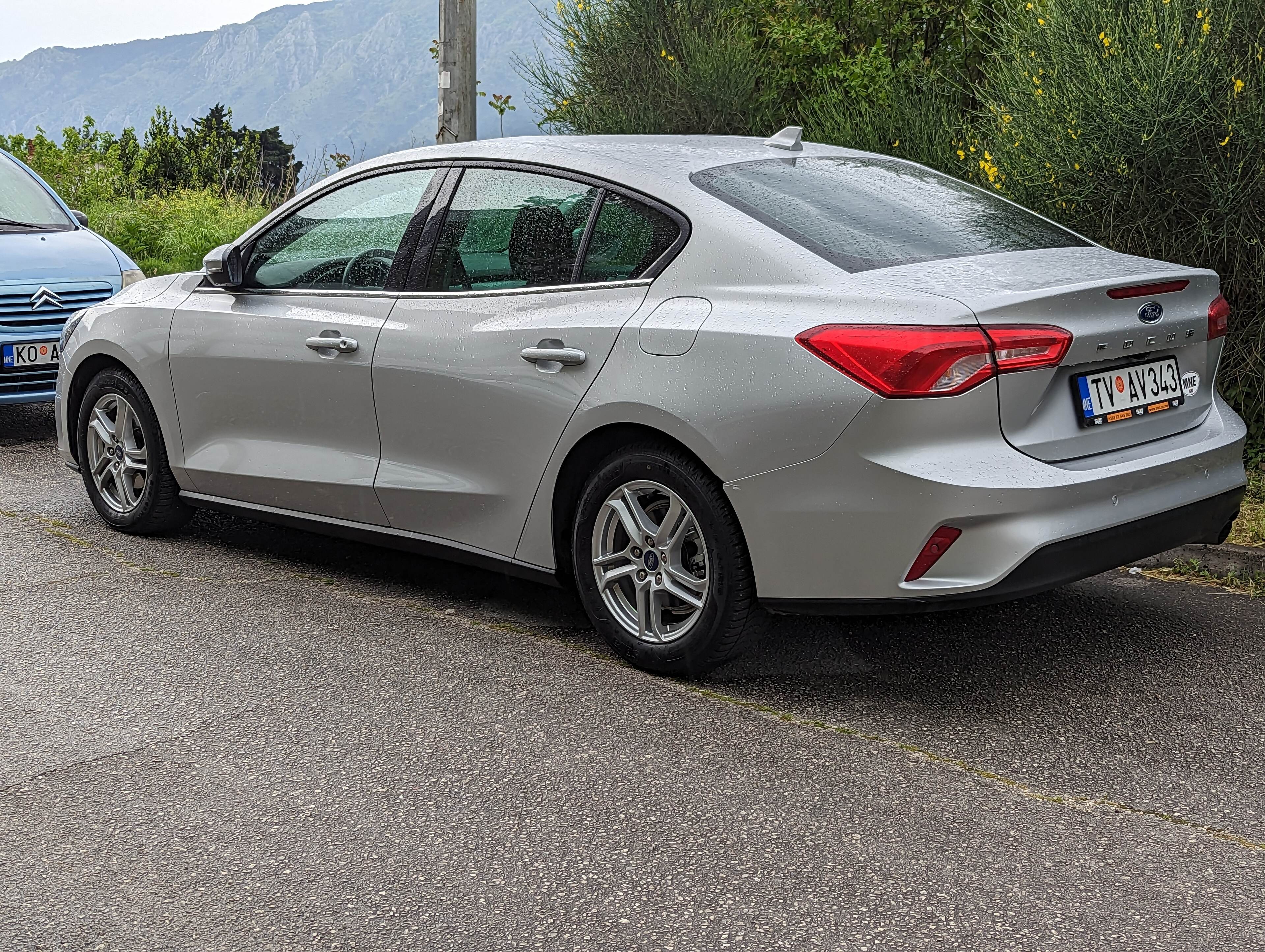 Pistonheads - The image shows a silver car parked on the side of a road. The car is positioned in such a way that it faces directly forward. It appears to be a modern sedan, with a sleek design and alloy wheels. In the background, there's a mountainous landscape, suggesting a rural or semi-rural setting. The sky above is overcast, hinting at recent or impending rain. There are no visible texts or distinctive markings on the car that would provide additional context or information about its make or model.