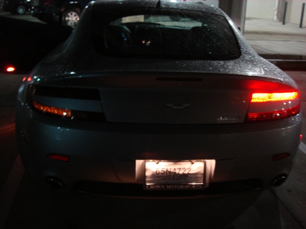 Pistonheads - The image captures the rear of a dark-colored sports car parked at night. The brake lights are lit, suggesting the car is stationary. Near the license plate, there's a bright light that might indicate a parking meter or streetlight. The overall scene conveys a sense of quiet solitude, with the car as the main focus against the backdrop of darkness.