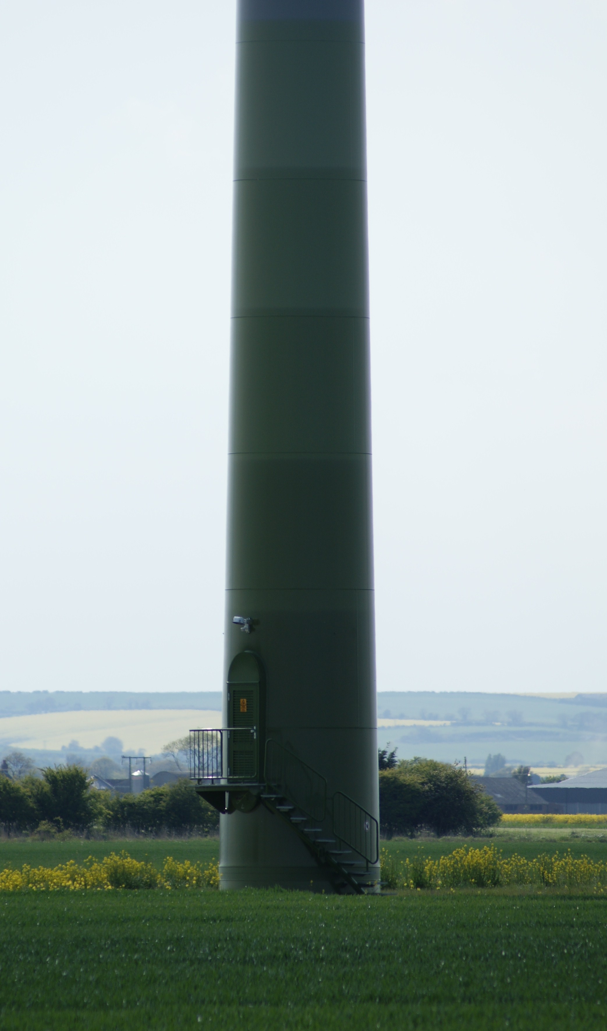 Random photos - Page 534 - Photography & Video - PistonHeads - The image features a tall tower-like structure with a spiral design, standing alone in a wide-open grassy field. The structure is cylindrical and appears to be made of a dark material, possibly metal, contrasting against the vibrant green of the surrounding grassland. The sky, visible in the background, is a clear blue with a few wispy clouds scattered across it. The absence of any other objects or structures in the vicinity emphasizes the towering nature of the structure.