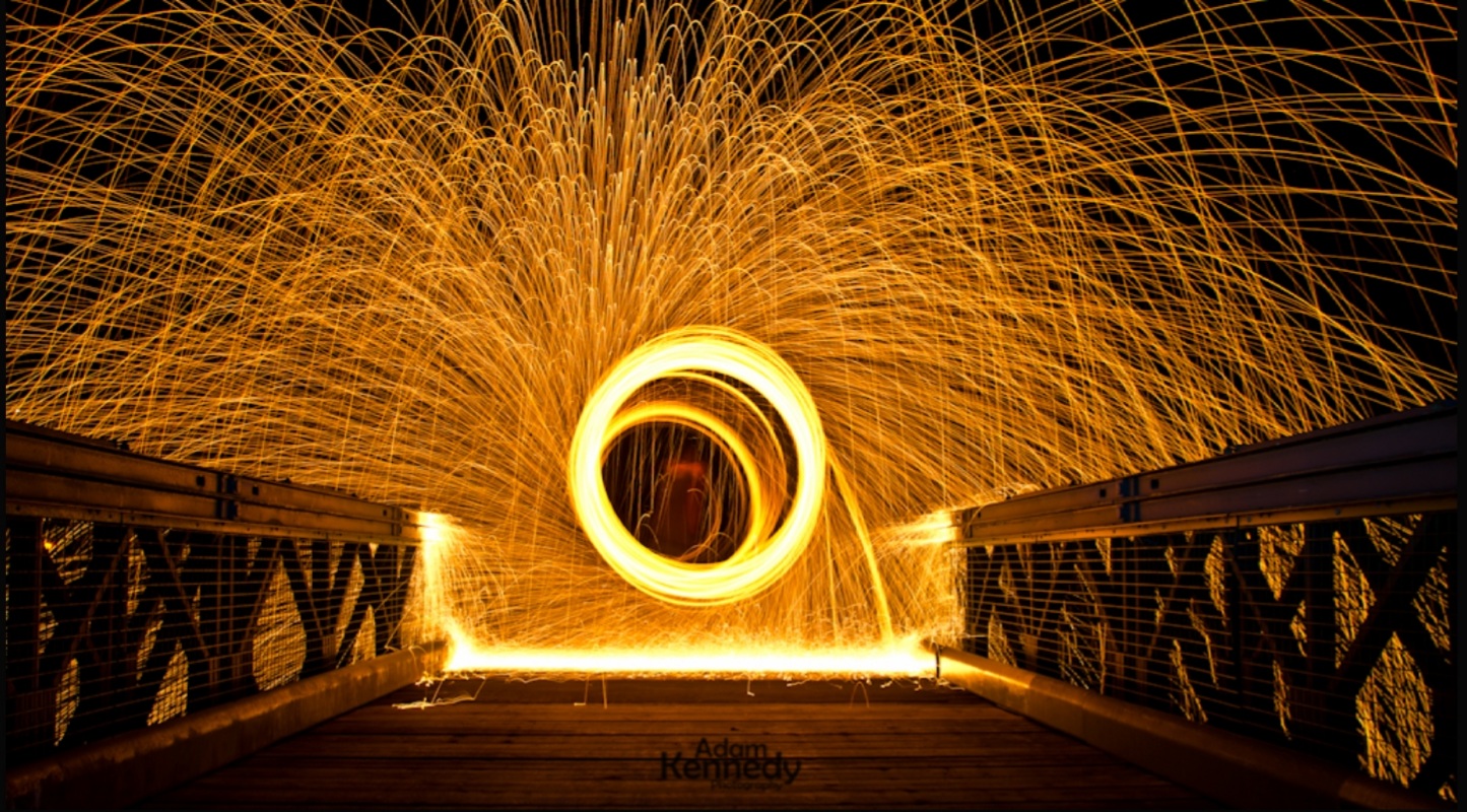 August 2021 Photo Competition - Your Best Shot - Page 1 - Photography & Video - PistonHeads UK - The image depicts an intriguing scene of a bridge at night, with the focus on the sparkles that are visible against the dark sky. These sparks create a mesmerizing pattern in the lower portion of the photo. Atop this lively display is a solitary figure standing still, appearing almost as if they're part of the sparks themselves due to their position relative to the camera angle and composition. The bridge serves as a platform for this person, with its handrail visible on the right side of the image. The overall scene suggests a creative or artistic endeavor, possibly involving photography or time-lapse techniques.