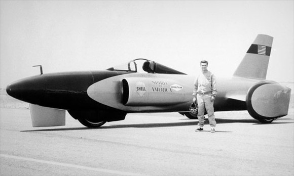 Bloodhound SSC Thread As Requested..... - Page 79 - General Gassing - PistonHeads - In the heart of a desolate Mayan plain, a single figure stands as the last bastion of human-made marvels. The plane, painted in striking shades of red, silver, and black, is a stark contrast to the monotony of the surroundings. Emblazoned on its side in bold black letters are the words "America Shale". The cockpit of the plane, a symbol of power and control, is open, inviting one to imagine soaring into the skies. The lone individual, possibly its pilot, stands next to the plane, adding a touch of life to this scene of human-made worship.