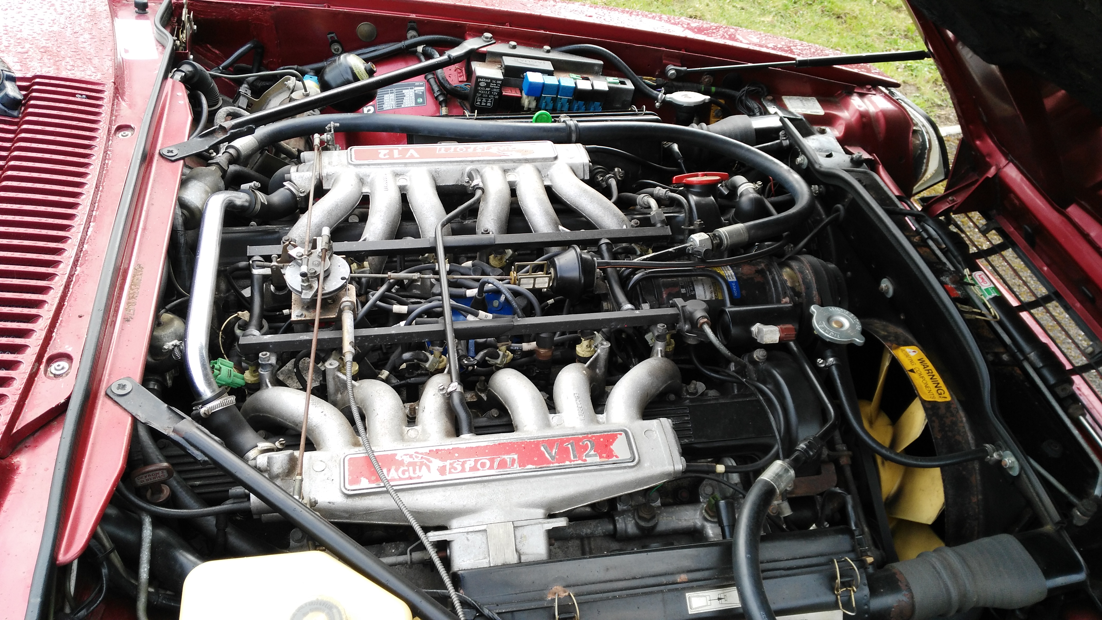 Best smoker barges 1-5 large [Vol 10] - Page 20 - General Gassing - PistonHeads - The image shows a close-up view of a red convertible car's engine compartment. The engine is prominently visible with its complex array of metal tubes and components. The yellow filter is sitting in front of the engine, likely part of an intake or exhaust system. The top of the hood is partially open, revealing more of the engine. The image does not include any text or branding.