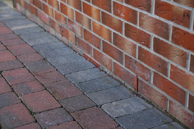 Air brick positioning - Page 1 - Homes, Gardens and DIY - PistonHeads - The image showcases a brick wall that stands out with its multicolored bricks. The wall appears to be constructed of red, brown, and yellow bricks, which blend together to create an interesting pattern. The wall is part of a larger brick building, suggesting a substantial structure. In the foreground of the image, a sidewalk with alternating red and gray bricks is partially visible, providing a contrasting element to the multicolored wall behind it.