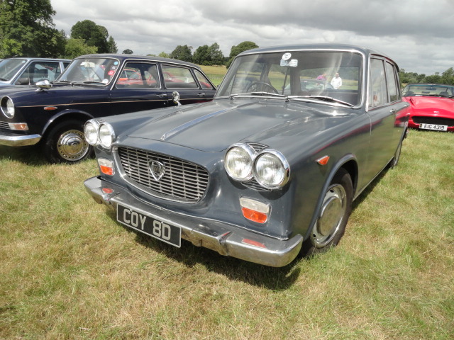 RE: Festival of the Unexceptional | PH Gallery - Page 8 - General Gassing - PistonHeads - The image shows a classic car parked in an outdoor setting. It is an old-style sedan with chrome details and a silver or light grey color scheme. The vehicle features the characteristic design elements of its era, such as round headlights and a grille that seems to be made of metal bars.

There are two other cars visible in the background; one appears to be a vintage vehicle as well, suggesting this may be part of a show or exhibition dedicated to classic automobiles. The setting includes grass underfoot, which indicates a lawn or field where such events might be held.