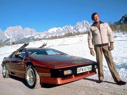 Your favourite car from the year you were born in... - Page 6 - General Gassing - PistonHeads - The image features a man standing next to an old, soft-top sports car in a snowy mountainous landscape. The man is wearing a white jacket and dark pants, and he has his hands in his pockets. The vehicle is red and appears to be an older model, possibly a DMC DeLorean. The setting suggests a winter vacation or a break from driving in cold weather. There are majestic mountains in the distance, indicating the photograph was taken in a mountainous region, possibly in the Alps or another such scenic area.