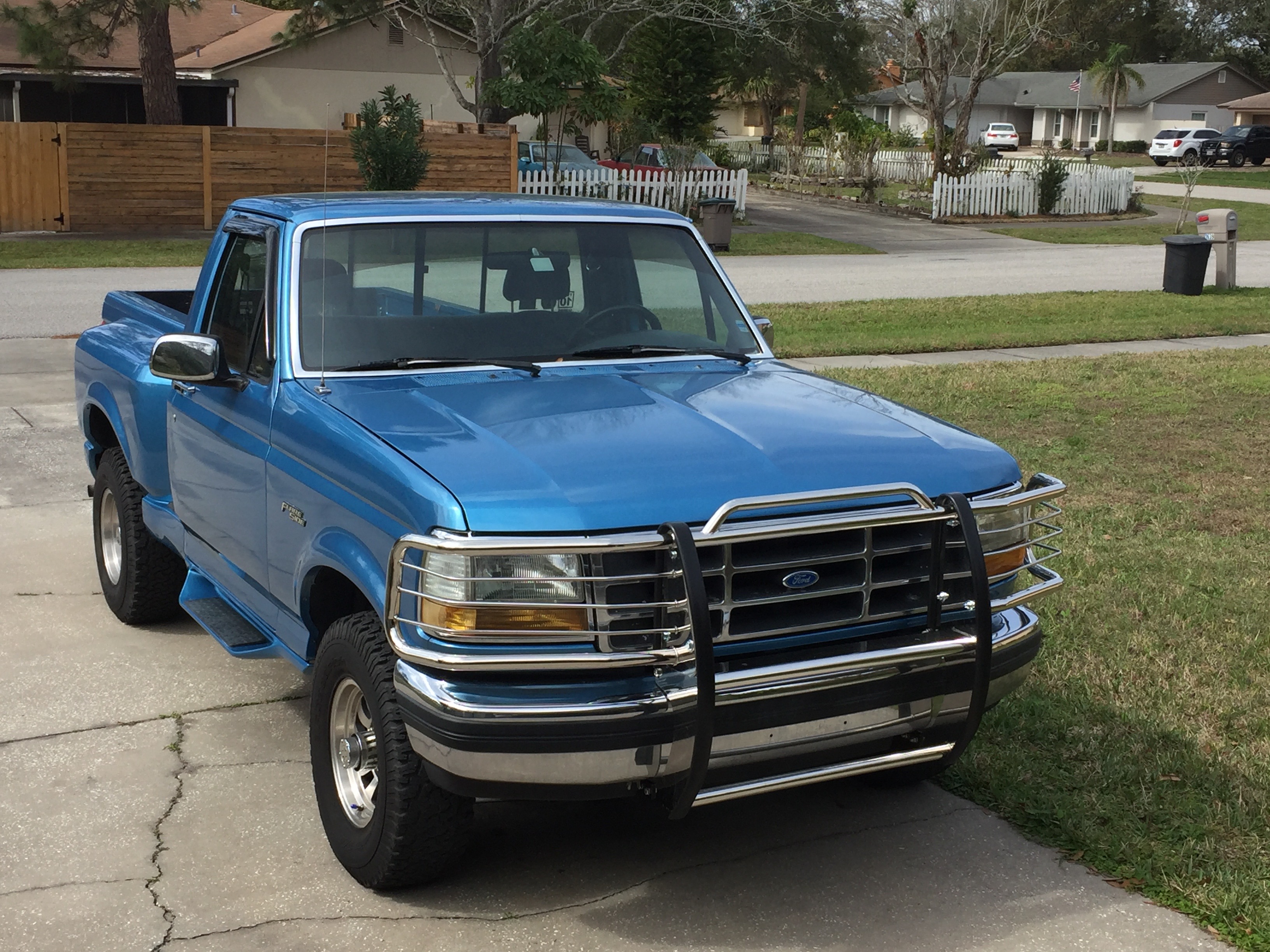 How many American trucks do I need? N+1 obviously! 1977 C10 - Page 3 - Readers' Cars - PistonHeads - The image shows a light blue pickup truck parked on a sidewalk in front of a residential area. The truck features a sleek design with chrome accents, and there's a black bumper guard visible. The surrounding environment includes a well-maintained lawn and a typical suburban setting with houses and a street in the background. There's a reflection on the ground from the truck, indicating that the photo was taken on a sunny day. The truck appears to be in good condition and is likely used for personal transportation or possibly work-related tasks.