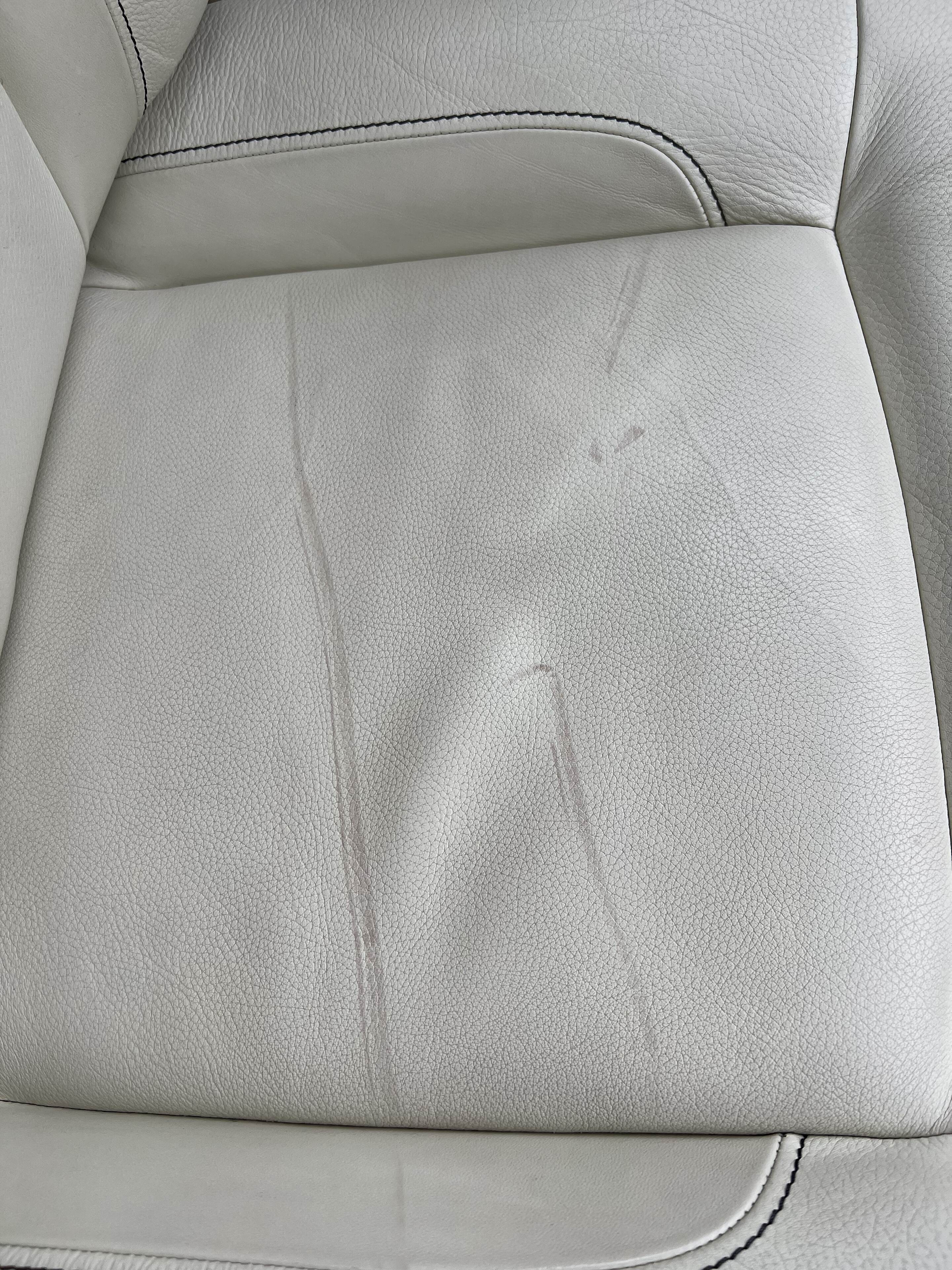 How to get this off my seat? - Page 1 - Bodywork & Detailing - PistonHeads UK - This image shows a close-up view of the headrest area on a white leather car seat. The material appears to be high-quality, and there are some visible scratches or abrasions on the upholstered fabric, which suggests that the seat has been used extensively or carelessly. The design of the headrest includes what seems to be an embossed pattern or texture. The photograph's focus is sharp enough to show these details and imperfections in the leather upholstery.