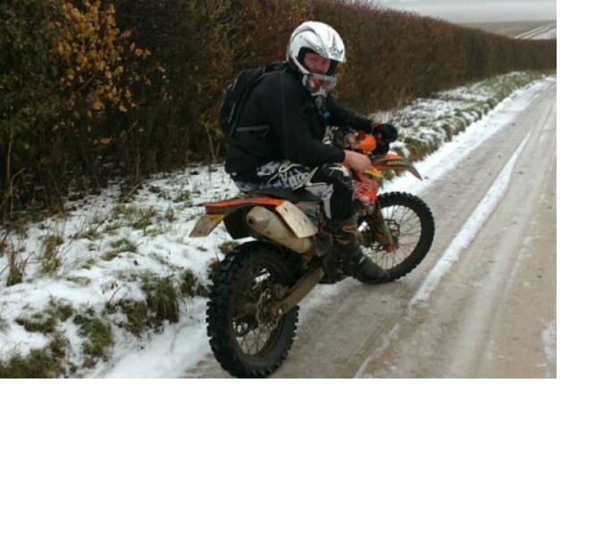 Winter laning. - Page 1 - Off Road - PistonHeads - This image shows a person riding a dirt bike off-road, possibly in a wooded area. The rider is wearing a full-face helmet, and the bike appears to be in motion with the front wheel lifted off the ground. The rider is dressed in winter gear, suggesting cold weather conditions. The surrounding terrain is covered in snow, and the rider has strapped a backpack on their back.