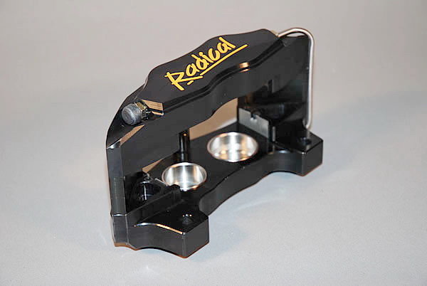 300mm brake upgrade for SR3  - Page 1 - Radical - PistonHeads - This image features a precision tool, which appears to be a base or mount for disassembling or configuring mechanisms or kits. It is predominantly black, with golden accents and English text that reads "REDIAM". The tool has a sleek design with metallic components, including latches and what could be a manual lever or locking mechanism. The craftsmanship suggests an artistic or bespoke touch, possibly indicating this is a custom or specialty item. The lighting and angle of the photo highlight the tool's details and elegance.