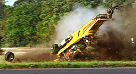 Spot the obvious defect - Page 5 - The Lounge - PistonHeads - The image captures a dramatic scene of a vehicle overturned on a road next to a grassy area. The car, which appears to be a race car due to its aerodynamic design, is on its side, indicating a significant impact or a high-speed collision. The surrounding area is filled with dust and debris, suggesting the speed at which the car was traveling before the accident.