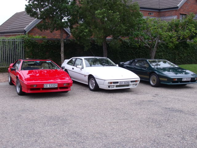 Greetings from a South African Esprit lover. - Page 1 - Esprit - PistonHeads - The image shows three vintage cars parked side by side on a paved surface. The car to the left is red with the license plate C5 1332, the middle car is white, and the car on the right is black with the license plate CX 2029. All cars appear to be of a similar model, possibly a Ferrari 308. They are positioned in front of a building and there is a branch of trees visible in the background. The style of the photograph suggests a casual or non-professional setting, with no visible text that provides additional context.