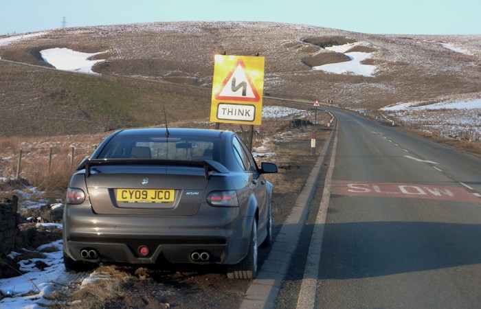 My VXR8 - pics taken today - Page 1 - Readers' Cars - PistonHeads - The image shows a gray car parked by the side of a road. In the background, there is a yellow road sign displaying the letter "M" along with the word "THINK." The road in the background appears to be a two-lane highway with snow visible on the ground. The sign seems to be in the rural countryside, suggesting a cautionary message for drivers.