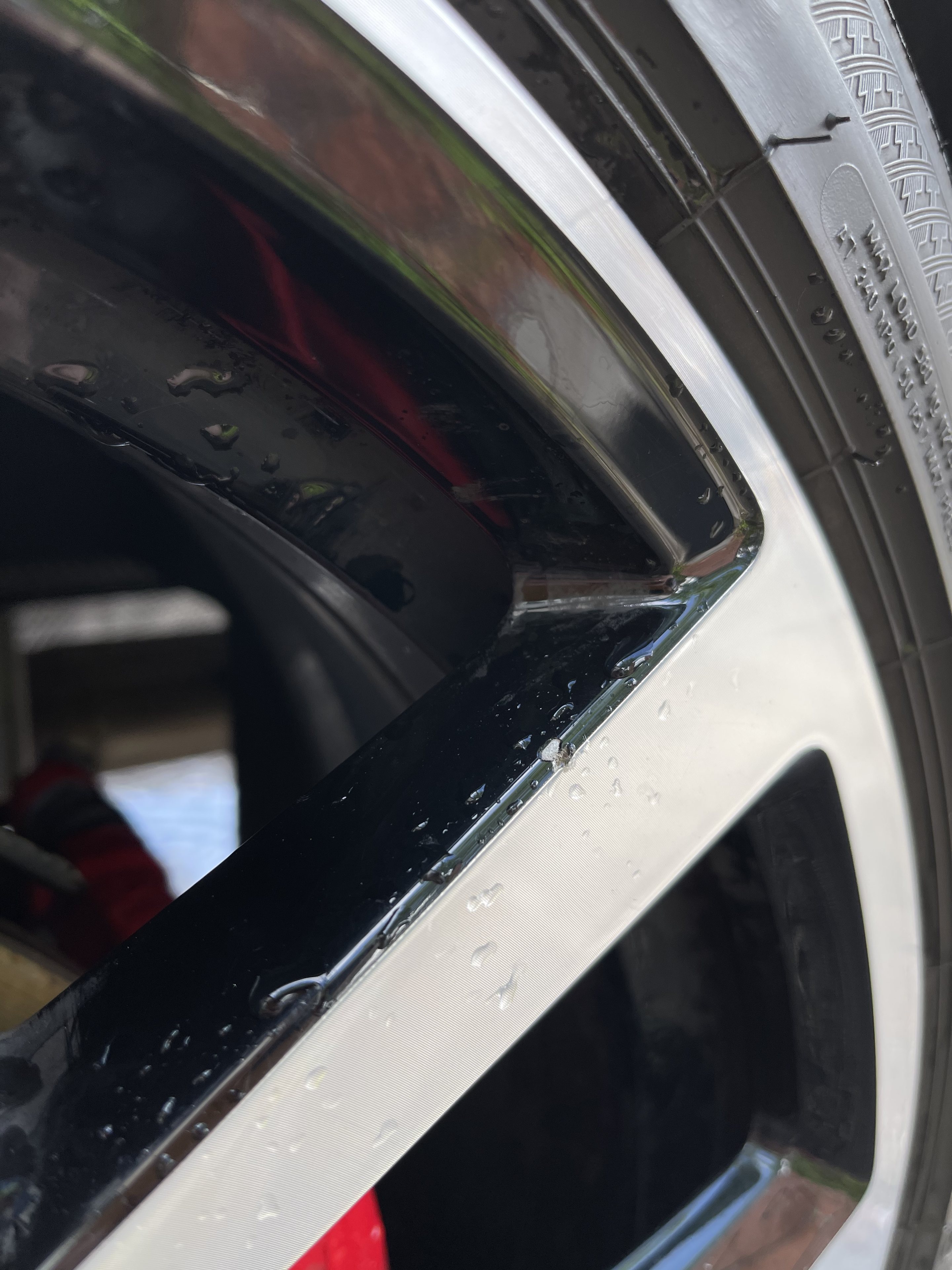 2020 AW (Mk6) Polo GTI+ - Page 1 - Readers' Cars - PistonHeads UK - The image shows a close-up view of a car tire, with the wheel well visible. There is a noticeable scratch on the wheel well area, which appears to be a metal surface. The tire itself is black and has a silver hubcap. It's positioned diagonally across the frame. The car's rim can also be seen, adding to the complexity of the scene. The background is nondescript, focusing attention on the wheel and its condition.