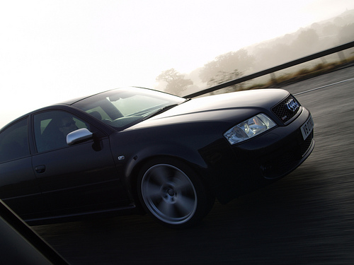 Pistonheads Dyno Mrc - The image features a striking black car in motion on what appears to be a foggy highway. The car is captured in the midst of a curve, its round headlights piercing the soft light and the driver's side mirrors reflecting a blur of the road in the background. The dark color of the car contrasts with the lighter, foggy tones that dominate the scenery, adding a sense of depth and distance. The car's design, with its sleek lines, aligns with the high-speed setting, suggesting an atmosphere of dynamic energy.