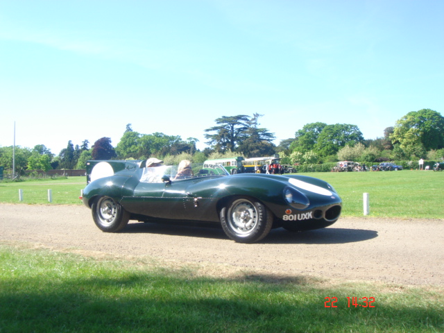 Pistonheads - This image captures a dynamic scene on a road. At the center of the frame, there's a green sports car with a convertible top, adding a touch of luxury to the image. The car is in motion, with the driver clearly visible, navigating through a picturesque landscape that includes not only the road but also a verdant field on the right.

In the background, there are trees lining the road and a cloudy sky overhead, suggesting either early morning or late afternoon light conditions. On the side of the road, there seems to be a small event or gathering, as evidenced by a few people standing at some distance, possibly observing the car.

Overall, this image tells a story of speed and luxury, set against a tranquil, natural backdrop. It's a snapshot of the contrast between the fast-paced world of sports cars and the unhurried pace of life in the countryside.