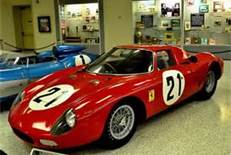 A red and white motorcycle parked in front of a building - Pistonheads - The image showcases a vibrant red sports car with the number 21 prominently displayed on its side. The car is the central focus of the image, gleaming under the indoor lighting. It is parked in a showroom setting, with other cars displayed in the background. The car appears to be a Ferrari, a well-known manufacturer, indicating its high-performance capabilities. The showroom itself has a spacious feel, with high ceilings that suggest it may be located in a building dedicated to car exhibitions or sales.