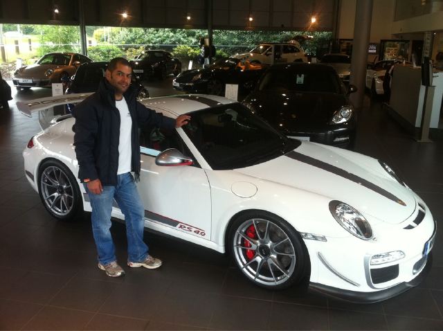 Lucky B'stard thread - Page 1 - Porsche General - PistonHeads - In the image, there is a man standing next to a sleek white Porsche sports car. The car features a black roof and stripes, along with silver rims and the number 40 prominently displayed. The man is dressed in a comfortable black jacket and a white t-shirt, wearing blue jeans that match the car's exterior. They are both situated in a showroom setting with elegant decor, showcasing the Porsche prominently in the foreground.