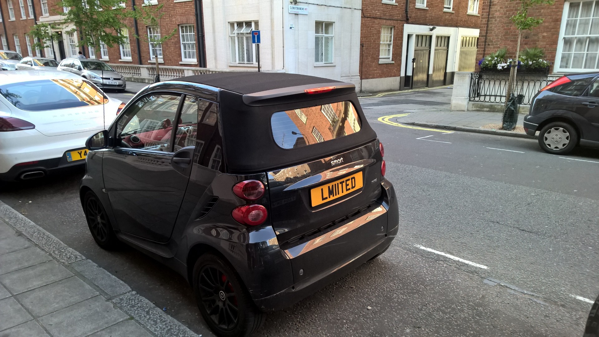 Real Good Number Plates : Vol 4 - Page 329 - General Gassing - PistonHeads - The image features a black urban smart vehicle parked on the side of a road during the day. The car is an LMU model and is adorned with a "Just Married" sign, suggesting that it might be part of a celebration or special occasion. The street is lined with parked cars, indicating that it is a populated area. On the sidewalk, there are a few potted plants and a sign, adding to the urban setting. The overall scene suggests a peaceful day in a city.