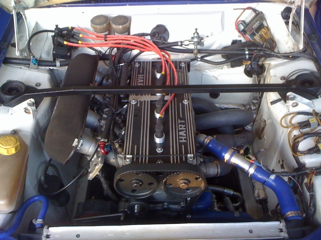 Pistonheads Bdr Oldschool - The image shows an interior view of an engine compartment, dominated by the black-and-silver engine and several red and blue wires running across it. Various mechanical parts, including the battery and other cylindrical components, are visible, suggesting a working or maintenance context. The hose and wiring connections indicate a possible custom installation or modification. The presence of both hose and wiring together may suggest a blend of modern electrics with traditional mechanical systems.