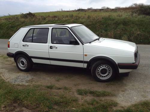 Classic (old, retro) cars for sale £0-5k - Page 287 - General Gassing - PistonHeads - The image features a white hatchback parked on a rocky surface alongside a road. The vehicle has a closed rear hatch and a visible license plate on the front. The surrounding area consists of green grassy terrain rising up to a grassy hill in the background. The sky above is mostly grey, suggesting an overcast or cloudy day.