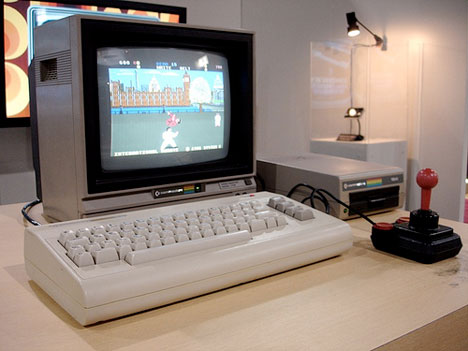 New turbo unit for the Gallardo - Page 1 - Gallardo/Huracan - PistonHeads - The image shows a white keyboard and a black game controller up close, set against a television, which displays an old-fashioned video game. In the background, there's a pink (or possibly red) dot design and a painting with rounded shapes. The keyboard and controller are placed on a wooden table. The setting suggests someone's gaming station or desk used for work and gaming.