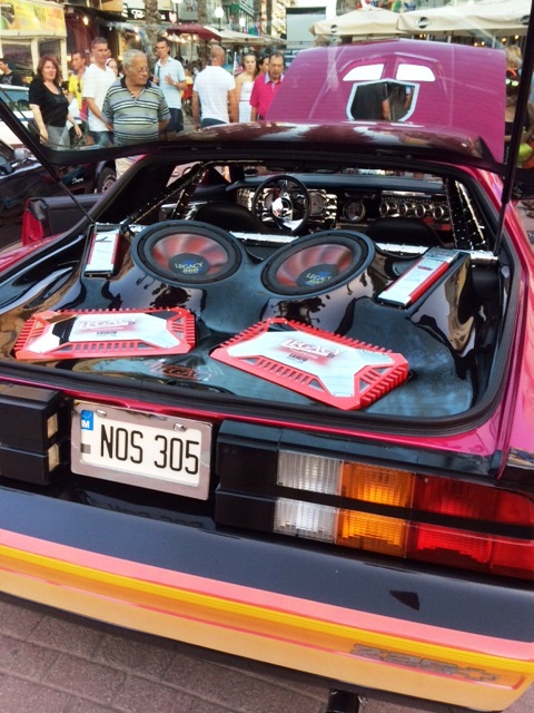 In Malta last week - Page 1 - Yank Motors - PistonHeads - The image showcases the distinctive rear section of a vehicle, which is predominantly black and purple. Two round speakers are prominently positioned on the trunk lid, while a license plate reading "NO5" is mounted above. The vehicle appears to be stationary, parked on a city street where other cars are visible. There's a sense of symmetry about the observer's viewpoint, giving a balanced look at the rear of the car.