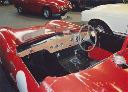 Early TVR Pictures - Page 35 - Classics - PistonHeads - The image captures a close-up view of the interior of a vintage sports car, possibly a vintage Alfa Romeo Spider. The vehicle features a grey steering wheel, a yellow panel with metal framework, and red seats. The car is parked, with other cars visible in the background. This scene exudes a nostalgic charm, harking back to the golden age of luxury cars.