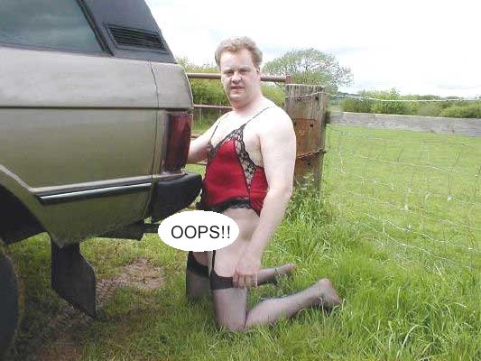 Classic Pistonheads Website - This image depicts a surreal scene where a man is kneeling on the grass, dresses as a woman wearing fishnet stockings, and directing his flow of urine into the tail light of a car. A disclaimer warning "OOPS!" is superimposed on the image, suggesting a momentary lapse in judgment or an unexpected turn of events. The surroundings include a fence, further adding to the unusualness of the scene. The humor and incongruity of the situation are likely the intention behind the image's staged nature.