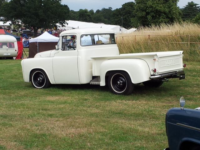 NSRA Hot Rod Supernats - Page 1 - Yank Motors - PistonHeads - The image features an old white crew cab pickup truck parked on a grassy field. The truck's distinctive design elements include a chrome grille, whitewalls, and a bed cover on its flatbed. In the background, there is a collection of colorful tents and several people can be seen among the tents. The overall scene suggests a festive or crowded outdoor event.