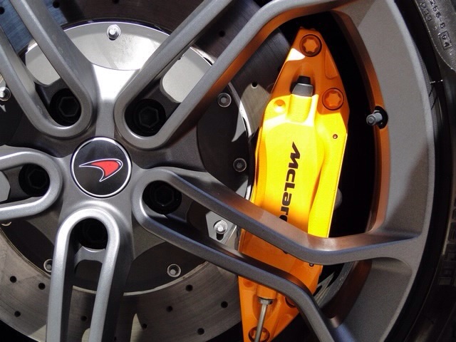 McLaren brake caliper - Page 1 - McLaren - PistonHeads - The image shows a close-up view of a performance wheel and brake caliper, focusing on the details of the components. The wheel features distinctive lime green and black colors, with the brand's logo on the center cap. The brake caliper is partially exposed, indicating its position behind the rotor. The spokes of the wheel are prominently visible, further emphasizing the vehicle's racing or performance appearance. The image is rich in detail, emphasizing the precision and craftsmanship of the automotive part.