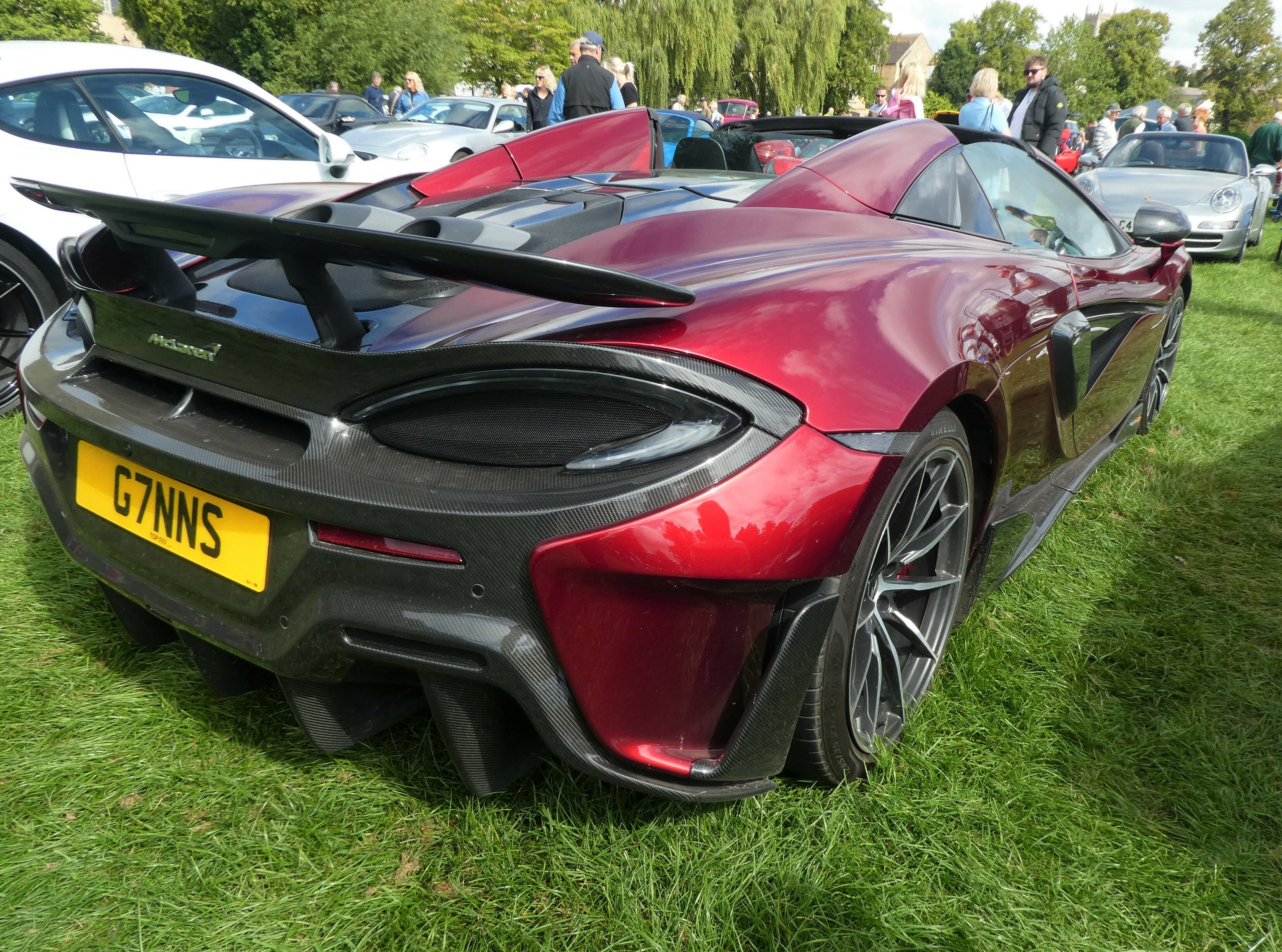 Pistonheads - The image showcases a striking red sports car parked on grass. It features a sleek and aerodynamic design with a prominent rear wing, suggesting high performance capabilities. The vehicle has the registration plate "759SW" visible, along with the Mercedes-Benz emblem, indicating it's an electric model. In the background, other cars are partially visible, hinting at a gathering or event where car enthusiasts might appreciate this sports car.