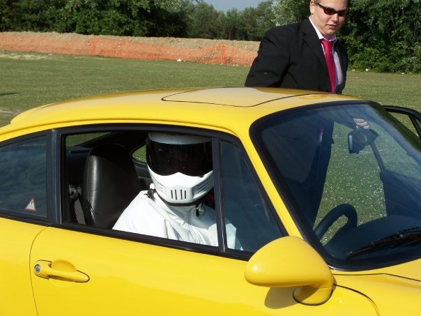 Wedding Car - Help !!!!!!!! - Page 1 - Kent & Essex - PistonHeads - In the image, there's a striking contrast between the humble car and the pompous man stepping out of it. The car, a bright yellow convertible, catches the eye with its vibrant color and contemporary design. However, the true focal point of this image is the man, who is dressed in a stark black suit topped with a red tie. His attire is complemented by a matching red tie, suggesting a professional or formal occasion. Furthermore, he's wearing a white helmet, hinting that he might be ready for an adventure or perhaps preparing for an event related to safety or speed sports. The backdrop of the image is an overcast sky peeking through the trees, adding a touch of nature to the scene.