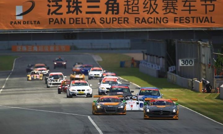 My new Radical in China... - Page 1 - Radical - PistonHeads - This image depicts a dynamic scene from a car race. The setting appears to be a track, possibly part of an event called the Pan Delta Super Racing Festival. A multitude of cars with various colors and designs are competing in the race, some in the foreground and others in the distance, indicating a long track. There is a large overhead banner that dominates the image, displaying the term "PAN DELTA" and the words "PAN DELTA SUPER RACING FESTIVAL" prominently, along with a logo and Chinese text, implying sponsorship or promotion of the event. The atmosphere suggests an action-packed and competitive event.