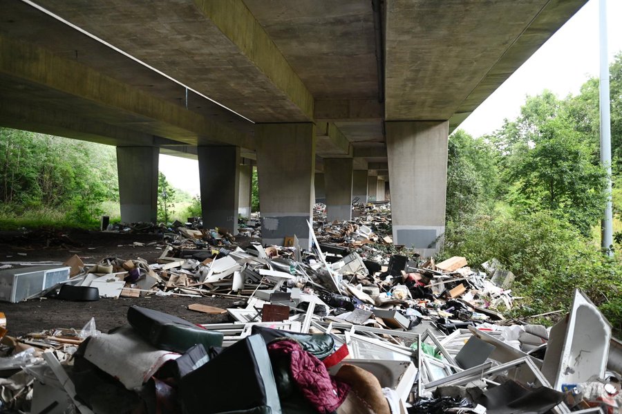 Scottish Referendum / Independence - Vol 10 - Page 496 - News, Politics & Economics - PistonHeads UK - The image shows an overpass that has been dumped with various items, including pieces of metal and debris. The area under the overpass is filled with trash, contributing to a sense of disorganization. There are no people visible in the scene, suggesting it's either too late or very early when no one would be around. In the background, there's a hint of greenery, which contrasts with the mess on the ground. The image captures an urban environment that has been neglected and is now littered with trash.