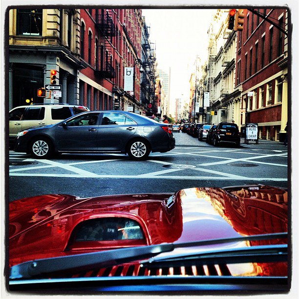 A car that is sitting in the street - Pistonheads - The image depicts an urban scene focusing on a snow-covered street intersection in a city. Cars and traffic lights occupy the foreground, while buildings tower above, creating a perspective view of the street. The contrast between the traffic lights and the vehicles, along with the wet, snowy road implies that the photo has been taken during a snowy day. The reflections on a car hood and windscreen suggest that the car is either parked nearby or moving through the intersection. The buildings' architectural style indicates an older city, possibly European, such as New York City with its similar streetscape and older buildings. The image captures the essence of winter city life, with the combination of vehicles, infrastructure, and architecture.