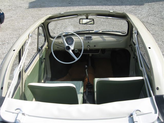 Pistonheads - This image features the interior of a small, compact car. The car has a white top with green sides and a black seat. The steering wheel is on the right side, and in the background, the vehicle's trunk can be seen. The car appears to be open, likely due to the removal of the passenger seat, which forms an additional seat on the right side of the image.