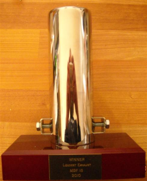 Pistonheads - The image features a metal trophy with a clear body and a red base. The trophy's reflections can be seen on its surface, suggesting that it is polished. The word "WINNER" is engraved on the base, indicating the award's purpose. The background is made of wooden planks, which provide a contrasting texture to the shiny metal. The gold part at the bottom of the trophy has a date on it, which is 2010, suggesting the trophy is for an anniversary or special event that took place in 2010.